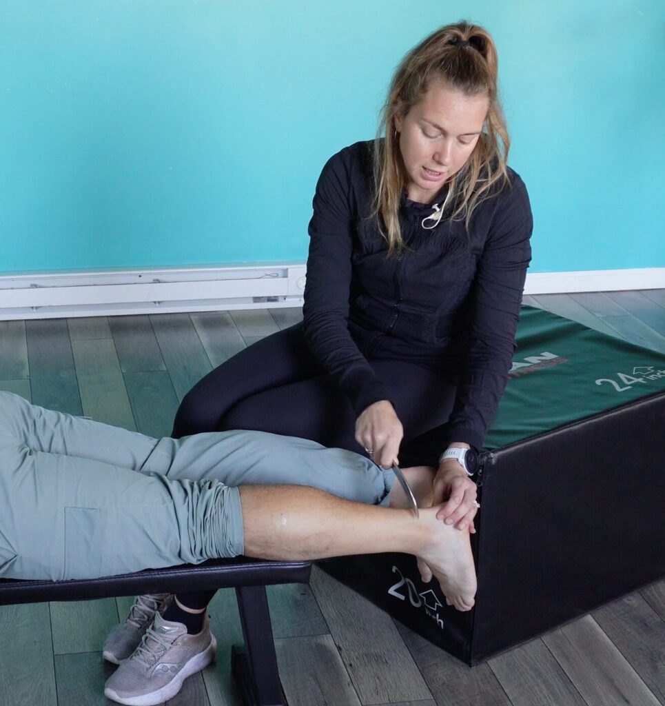 Dr. chloe using the muscle scraper to get behind the heel to help alleviate achilles tendinitis